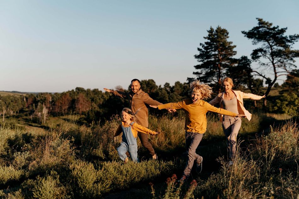 Familie läuft lachend durch die Natur bei Willingen Familie mit zwei Kindern genießt die Natur beim Familienurlaub in Willingen