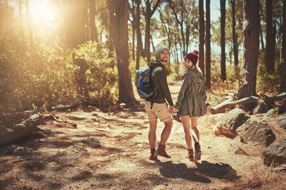 Paar beim Sommerurlaub in Willingen beim Wandern durch den Wald Fröhliches Paar wandert Hand in Hand durch den sonnigen Wald im Sauerland – Sommerurlaub im Hotel Eimberg